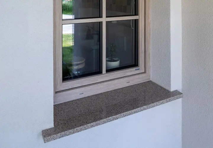 Granitowy parapet zewnętrzny wystaje ok. 5 cm, chroniąc elewację. Idealna proporcja, by wiedzieć, ile powinien wystawać parapet zewnętrzny.