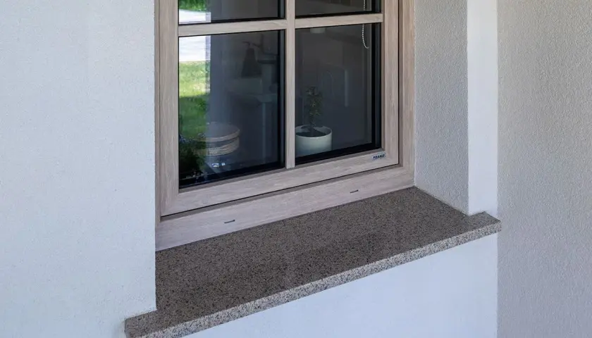 Granitowy parapet zewnętrzny wystaje ok. 5 cm, chroniąc elewację. Idealna proporcja, by wiedzieć, ile powinien wystawać parapet zewnętrzny.