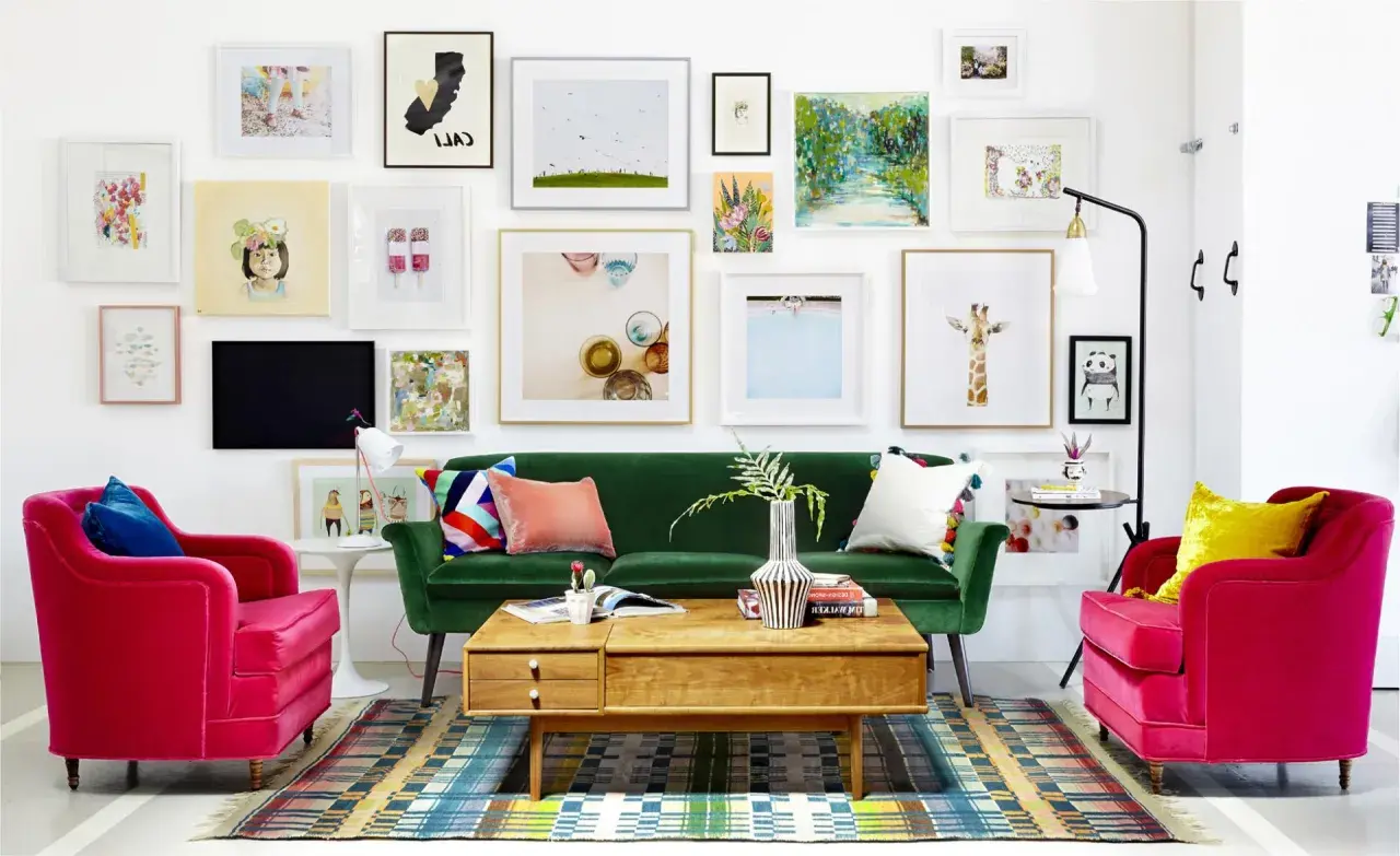Salon w stylu new eklektyzm: zielona sofa, fuksjowe fotele, kolorowy dywan i ściana pełna różnorodnych obrazów.