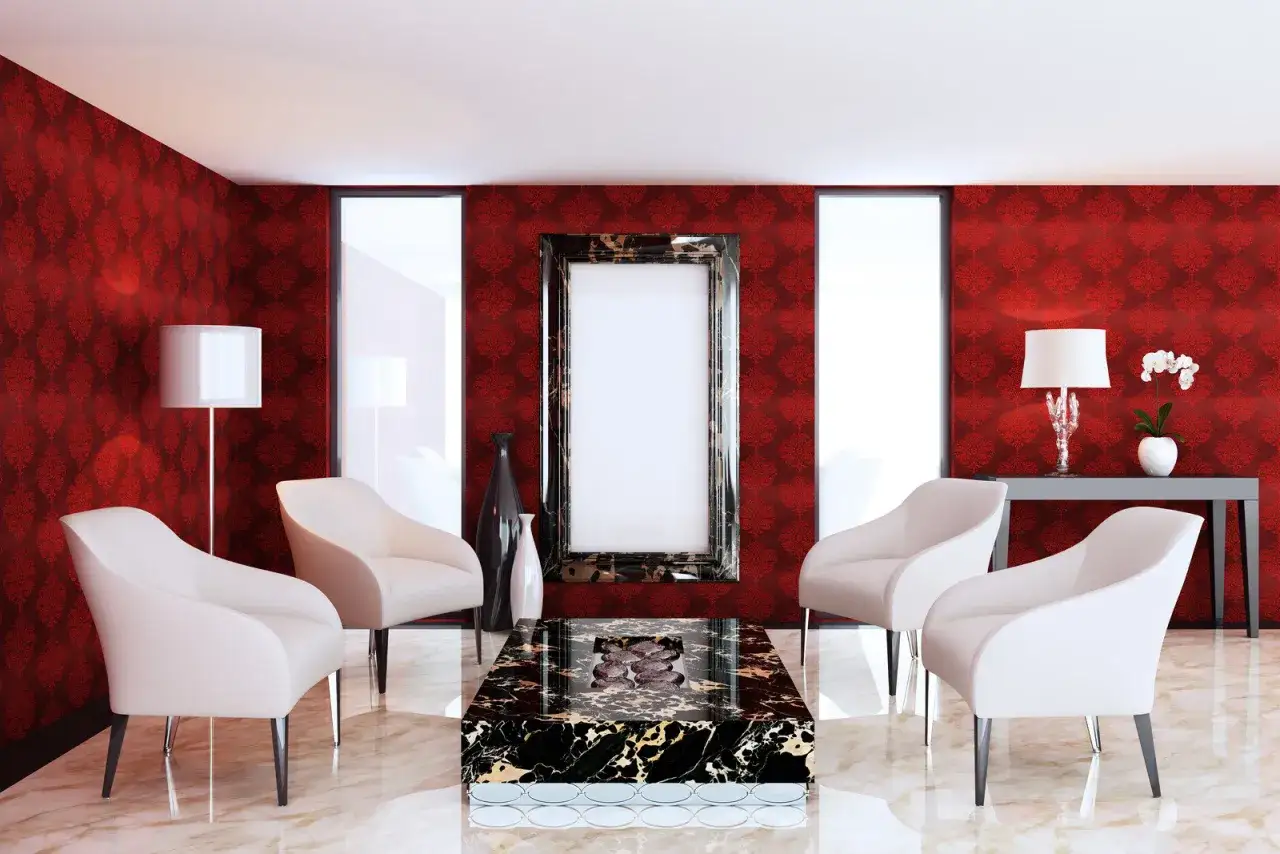 Elegancki salon z tapetą w ciemny czerwony kolor, cztery białe fotele, marmurowy stolik i ozdobne lustro.
